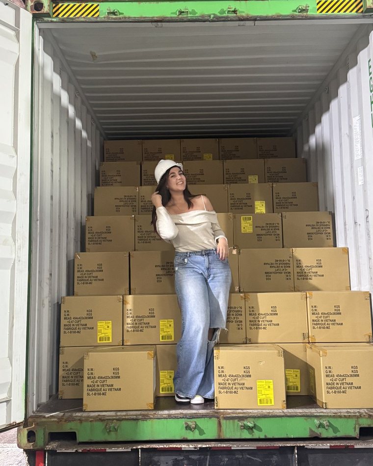 Valeria Bernardo dentro de un contenedor de importación, de pie entre la mercadería